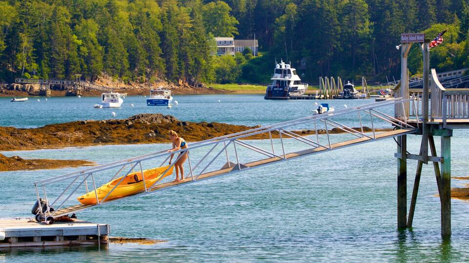 A wooden bridge over water with a yellow kayak, boats, and a motel in the background.