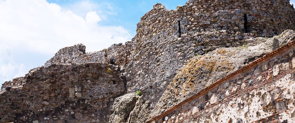 A stone ruin with layered walls and a clear sky.
