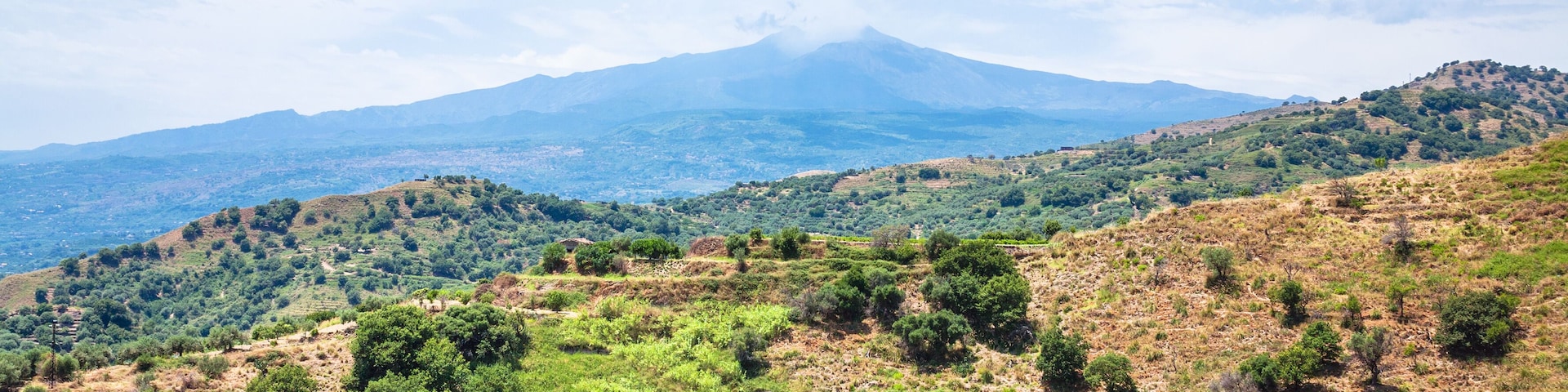 Un paisaje montañoso con un volcán destacado al fondo.