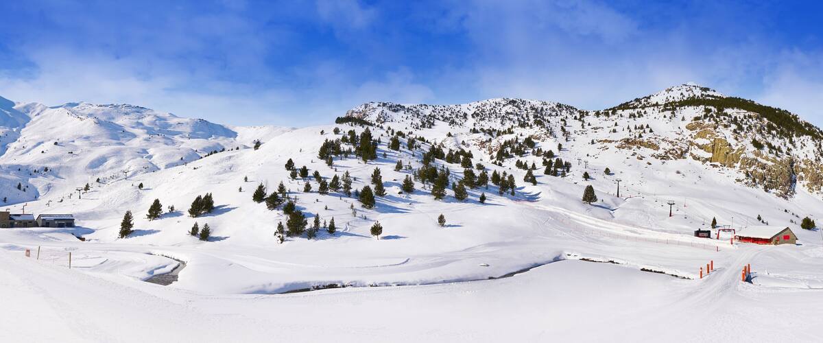 A snow-covered mountain with ski slopes, a ski lift, and a red building.