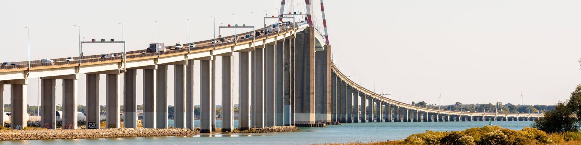 A large bridge with multiple lanes of traffic, spanning over a body of water.