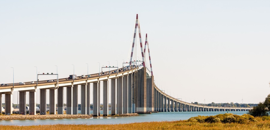 A large bridge with multiple lanes of traffic, spanning over a body of water.