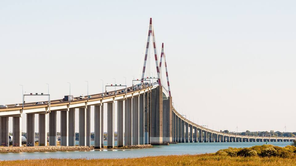 A large bridge with multiple lanes of traffic, spanning over a body of water.