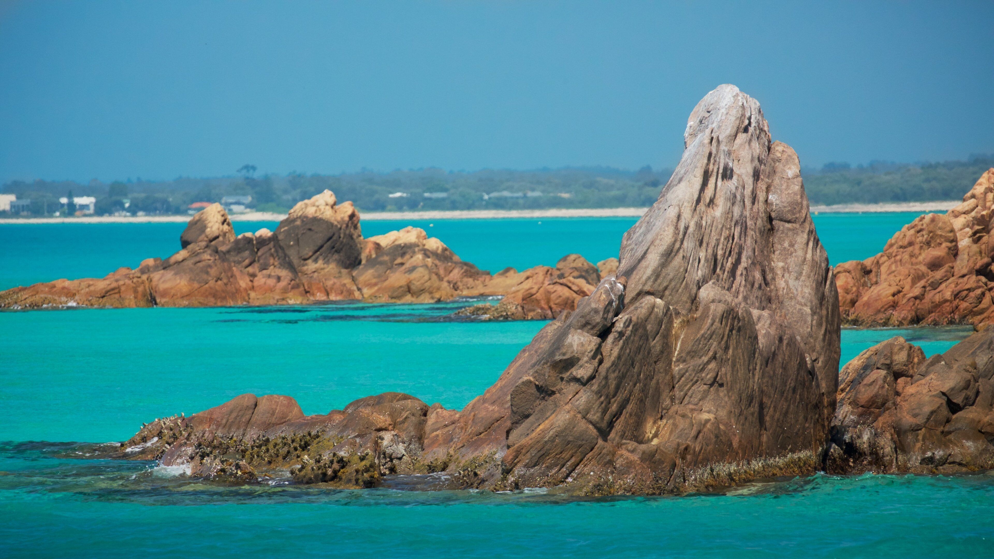 A rocky coastline with clear turquoise waters and a prominent rock formation in the foreground.