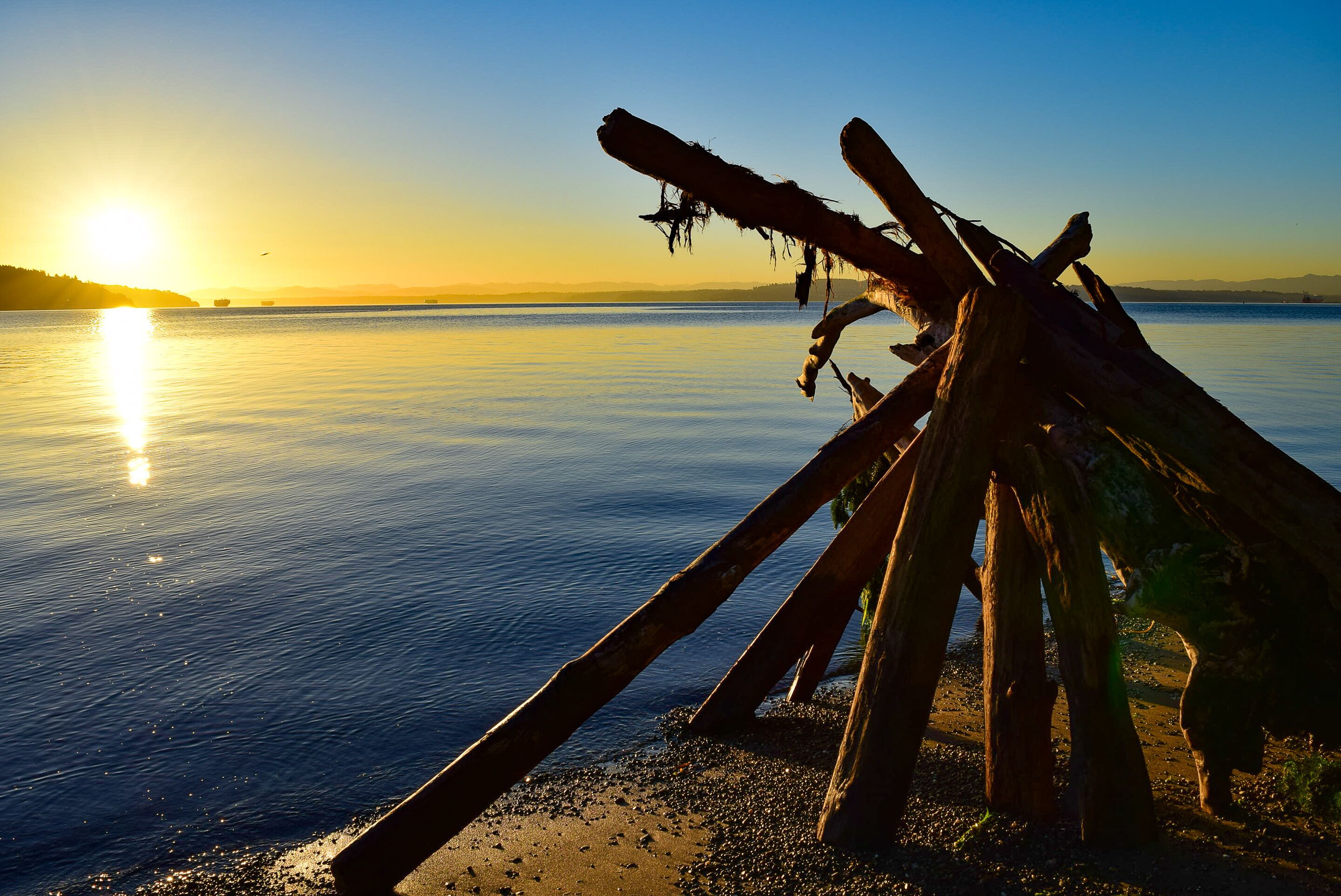 A calm lake at sunset with a wooden structure on the shore.