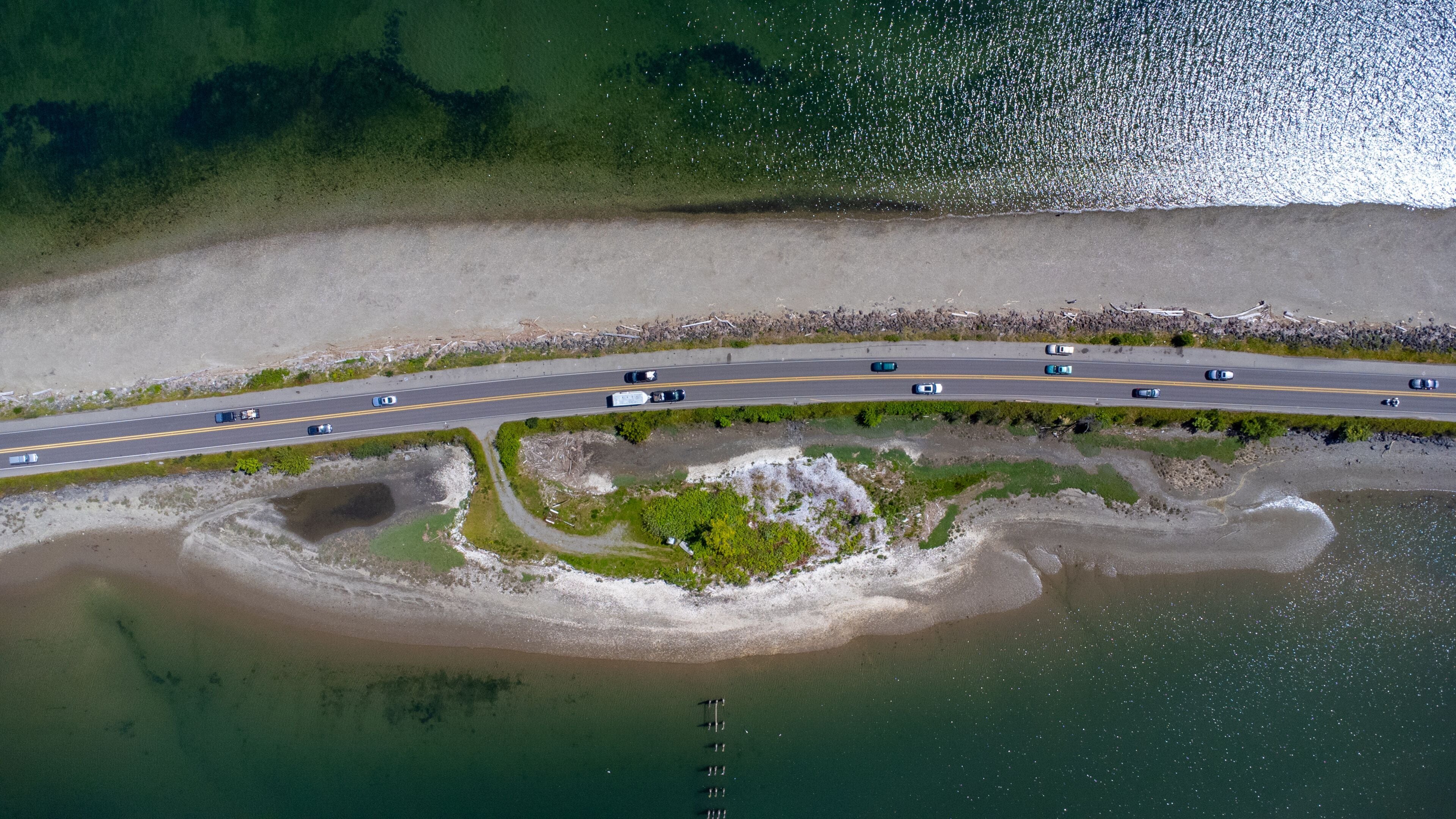 A coastal highway with a beach and a small island.