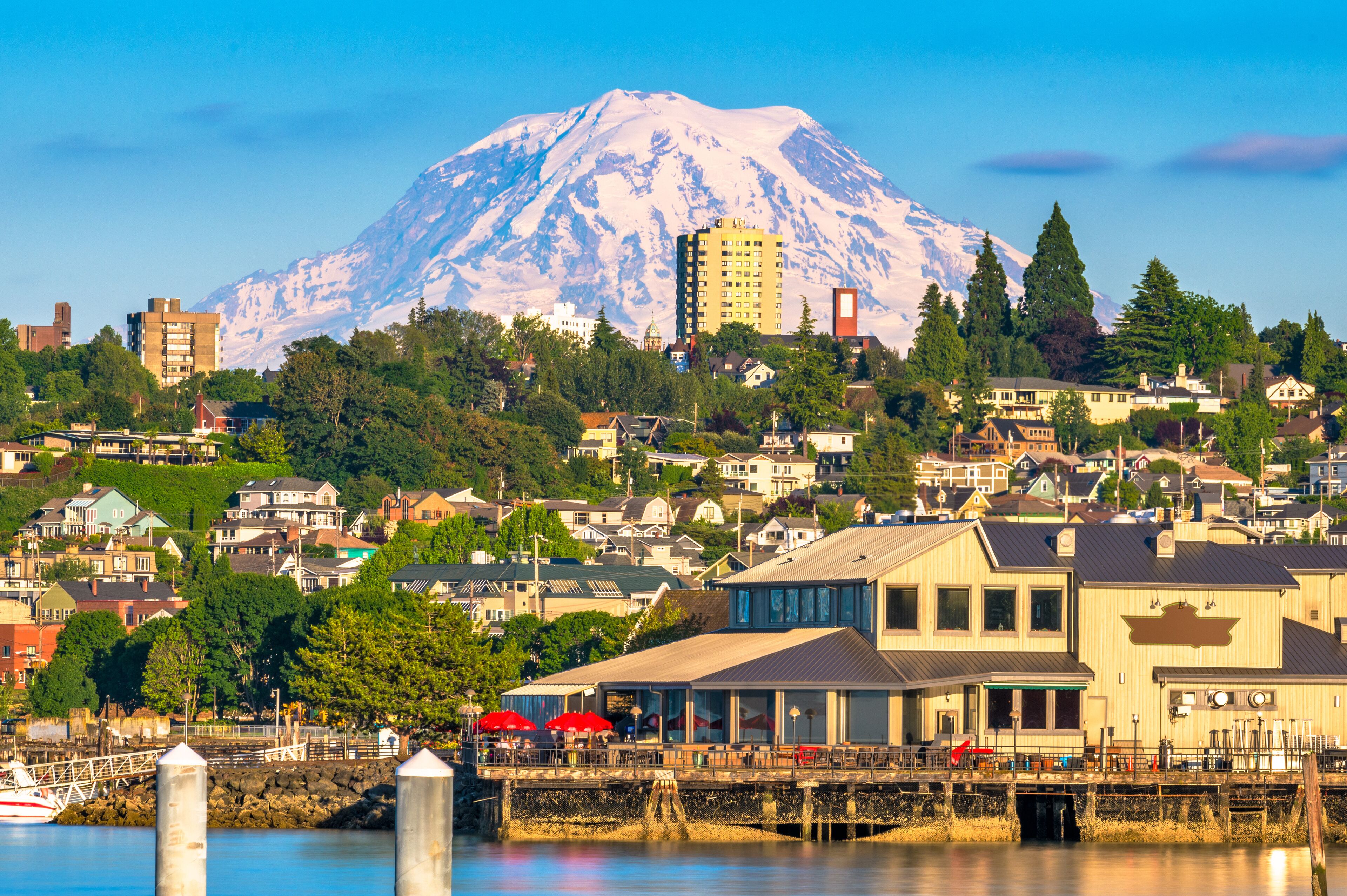 A coastal town with a prominent snow-capped mountain in the background.