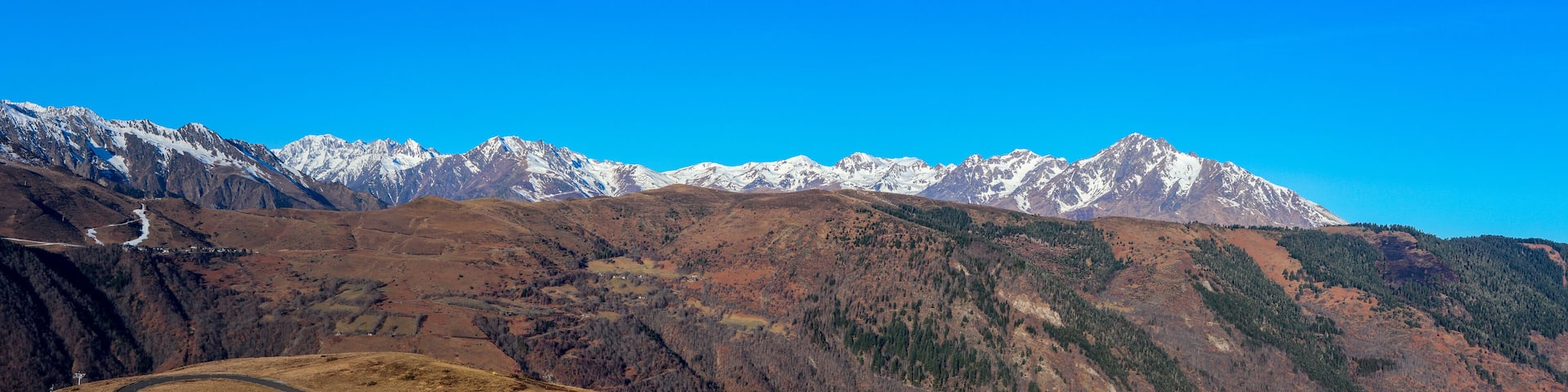 A mountain range with snow-capped peaks under a clear blue sky.