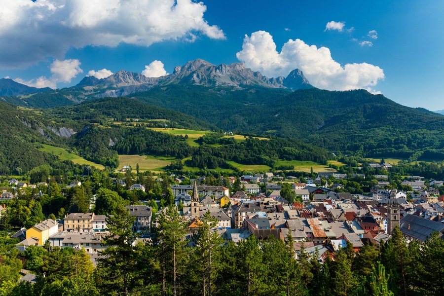 A town nestled in a valley with a mountain range in the background.