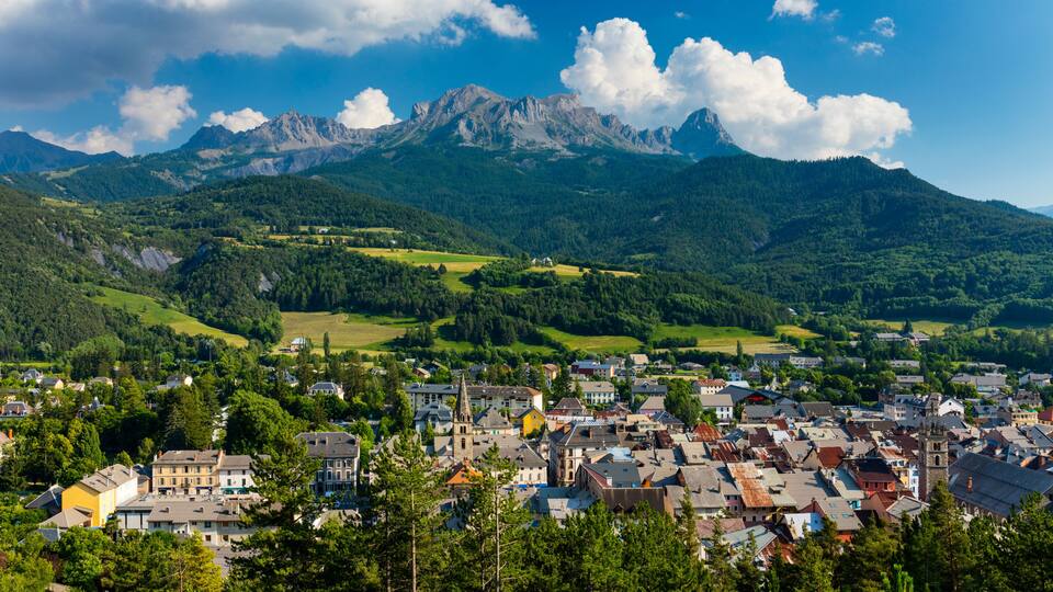 A town nestled in a valley with a mountain range in the background.
