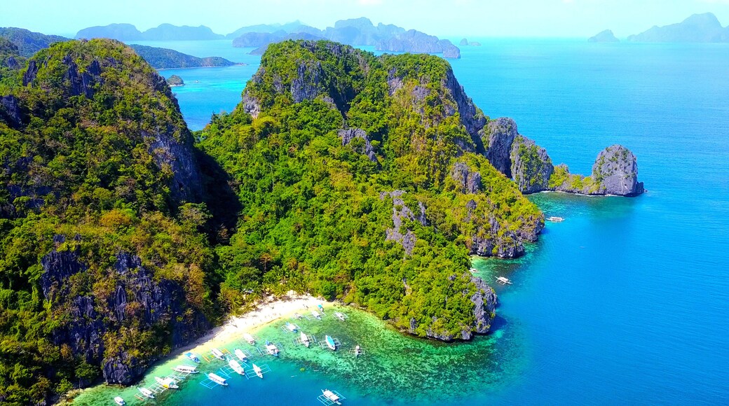 Exotic Beach Cove With Catamaran Style Boats On Rocky Tropical Island - El Nido, Palawan, Philippines - Aerial View