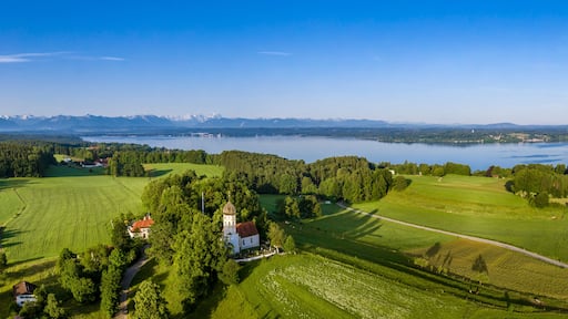 Ein See, umgeben von Bergen, einer Kirche und üppigen grünen Feldern.