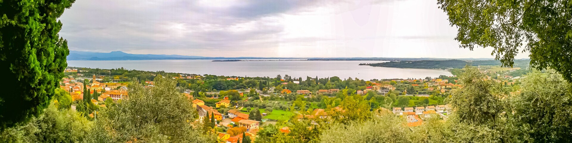 A coastal town with red-roofed buildings, surrounded by greenery and a large body of water.