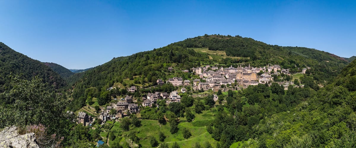 A village nestled in a valley surrounded by lush green hills.
