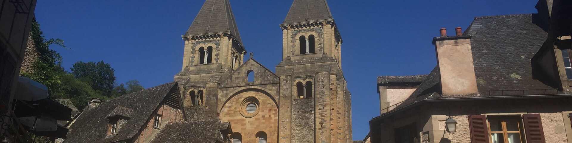 Una iglesia histórica con dos torres y una calle tradicional europea llena de gente.