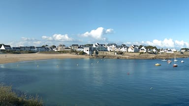Une ville côtière avec des maisons le long de la plage, des bateaux sur l’eau et un ciel dégagé.