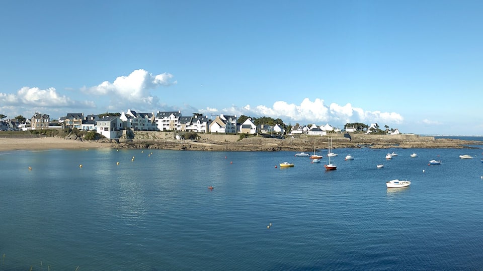 A coastal town with houses along the shore, boats in the water, and a clear sky.