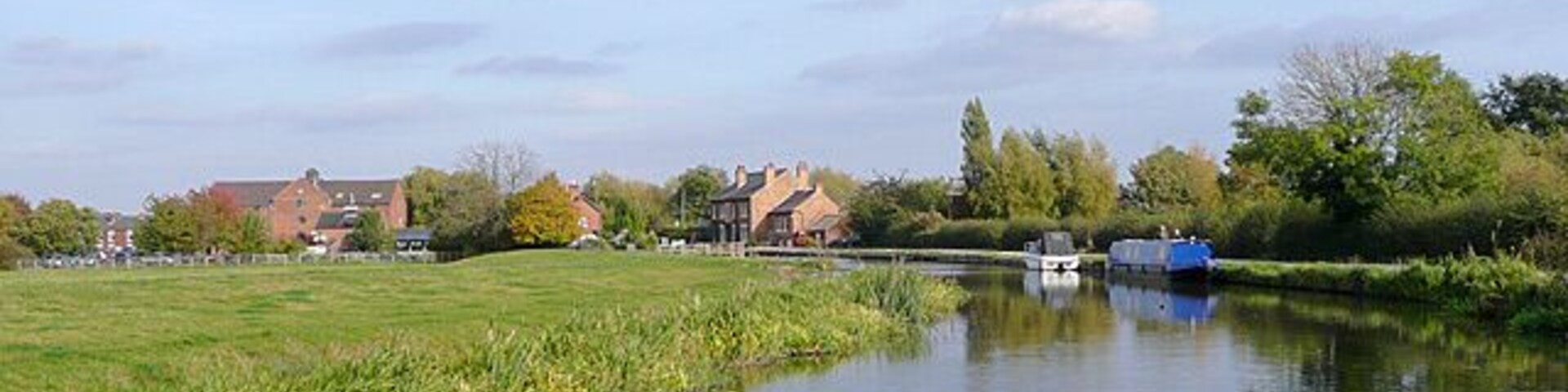 Trent and Mersey Canal approaching Shardlow, Derbyshire. Shardlow Lock is by the cottages on the bend beyond the blue boat. The canal terminates at Derwent Mouth one mile further on.