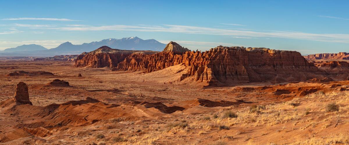 A desert landscape with prominent red rock formations and distant mountains under a clear sky.