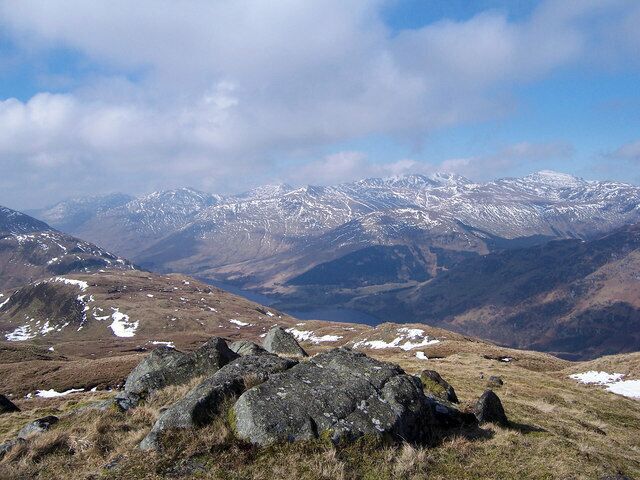 A mountainous landscape with rocky terrain and snow-capped peaks in the distance.