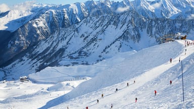 Skiers are sliding down snow-covered hill on skis at the Cirque du Lys. There is range of mountains (Soum de Mauloc) in the background