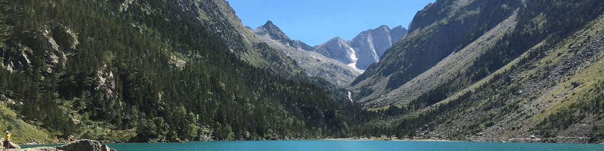 Eine Gruppe von Menschen sitzt an einem See, umgeben von Bergen.