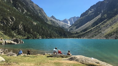 Um grupo de pessoas sentadas à beira de um lago, com montanhas ao redor.