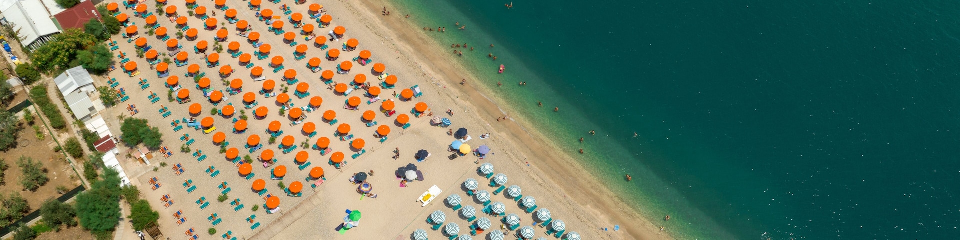 Vista aérea de uma praia com fileiras de guarda-sóis e cadeões de praia.