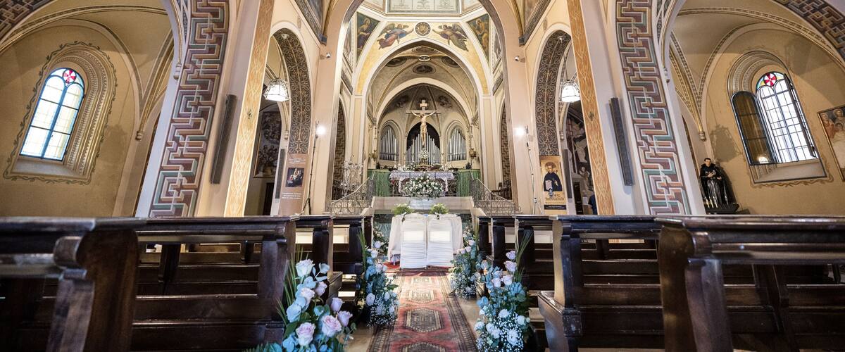 An ornate church interior with high vaulted ceilings, arched windows, and a central altar.