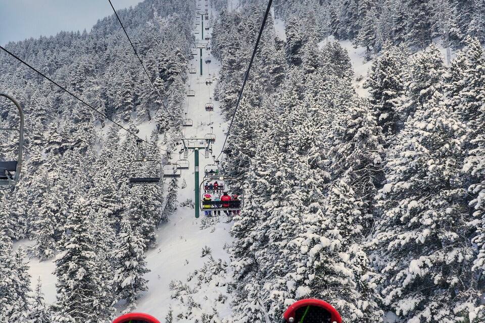 Eine Seilbahn mit schneebedeckten Bäumen und blauem Himmel.