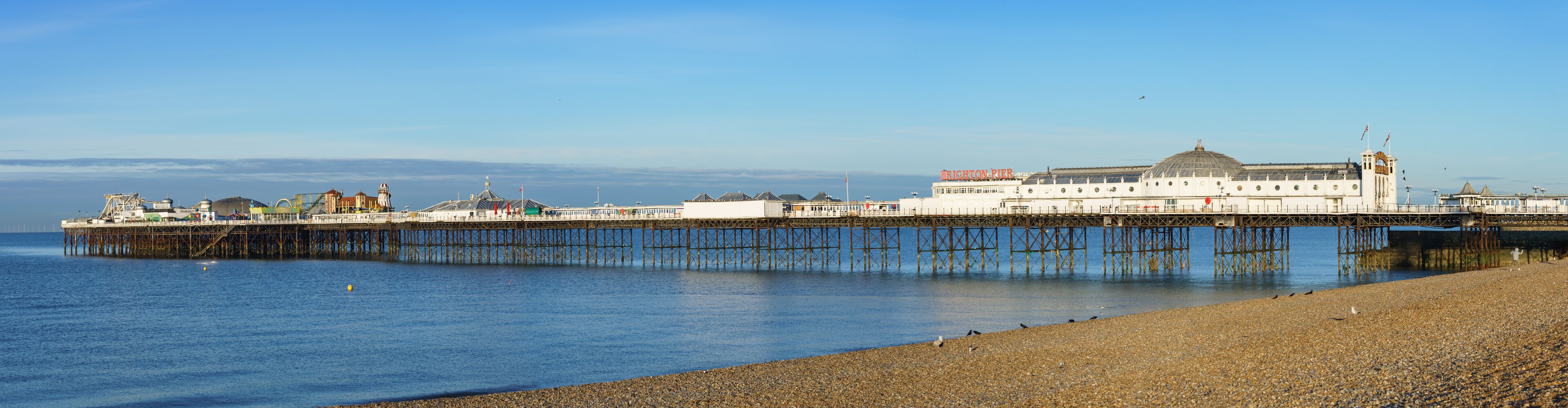 Un muelle con un gran edificio que dice 'BRIGHTON PIER' extendiéndose sobre el agua.
