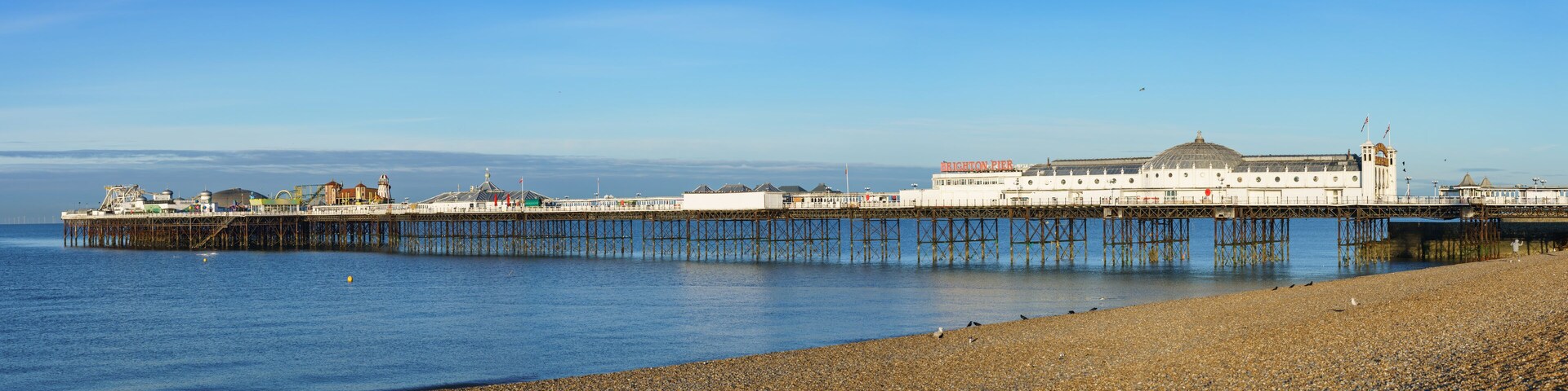Un muelle con un gran edificio que dice 'BRIGHTON PIER' extendiéndose sobre el agua.