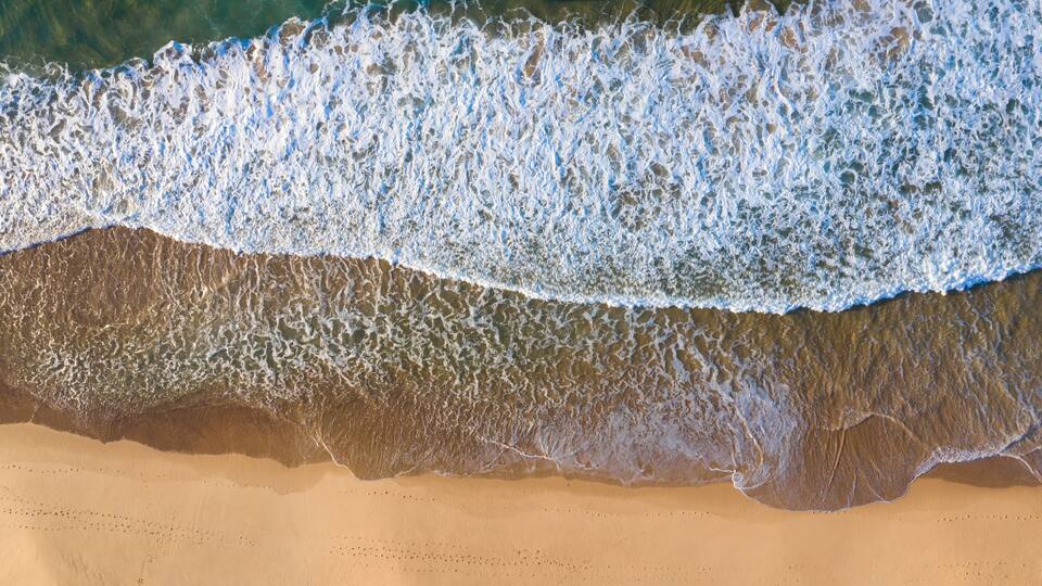 A sandy beach with waves breaking on the shore.