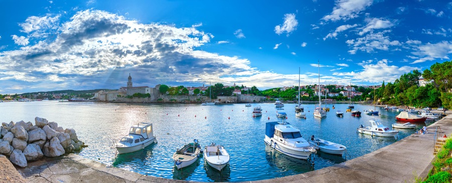 A harbor with boats, a lighthouse, and a town in the background.