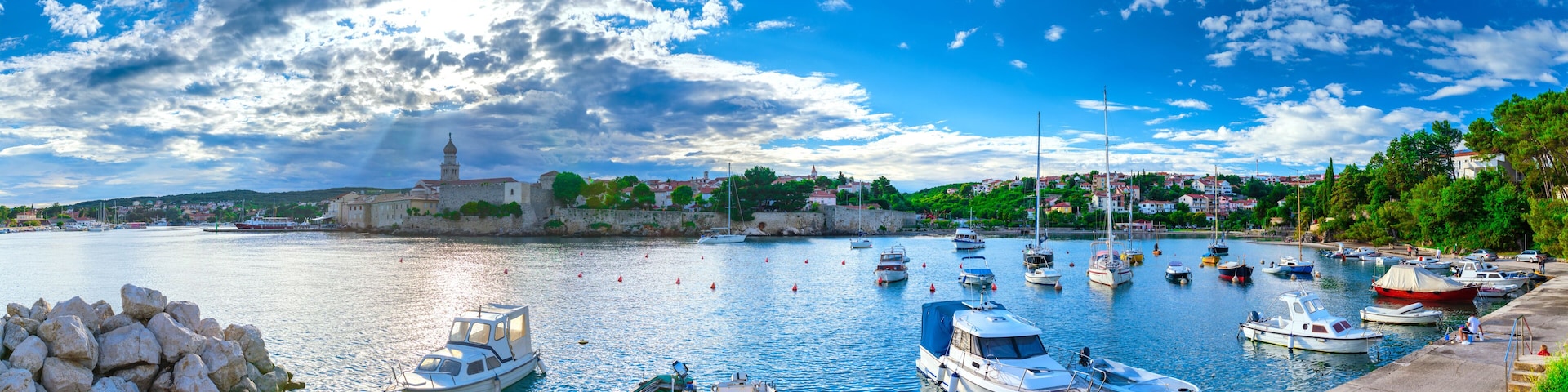 A harbor with boats, a lighthouse, and a town in the background.
