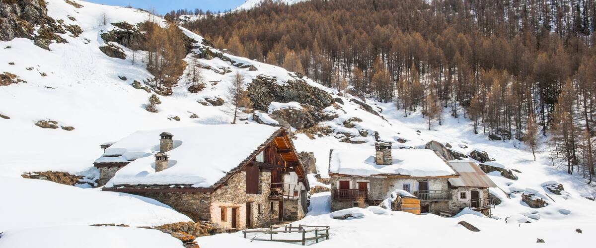 A snow-covered village with stone houses and a mountainous backdrop.