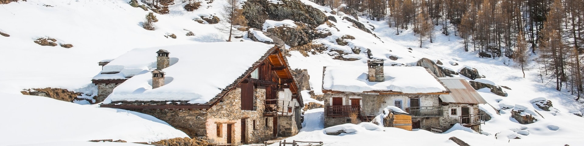 A snow-covered village with stone houses and a mountainous backdrop.