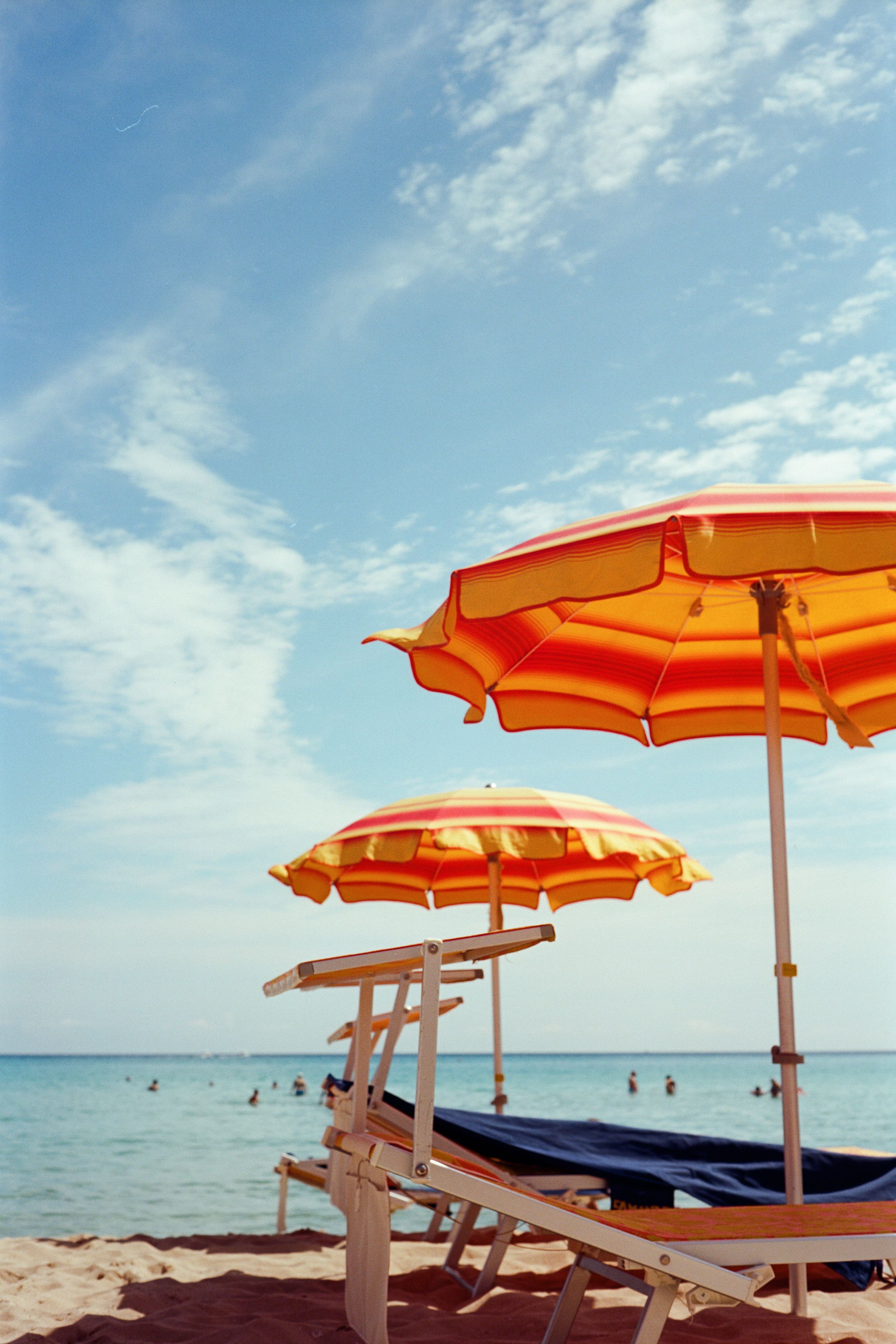 Beach umbrellas and lounge chairs on a sandy beach with the ocean in the background.