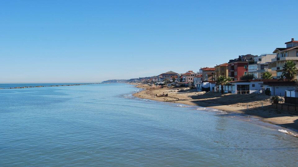 A coastal town with a beach, houses, and a clear blue sky.