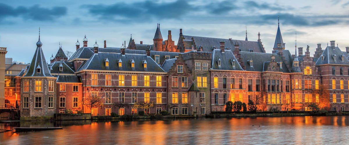 A historic building with multiple spires and a river in the foreground.