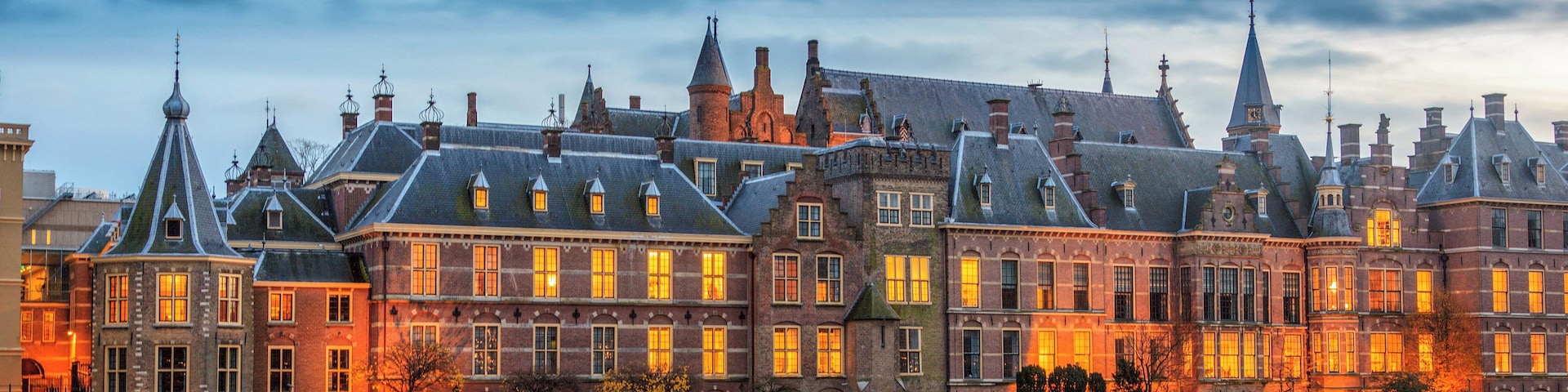A historic building with multiple spires and a river in the foreground.