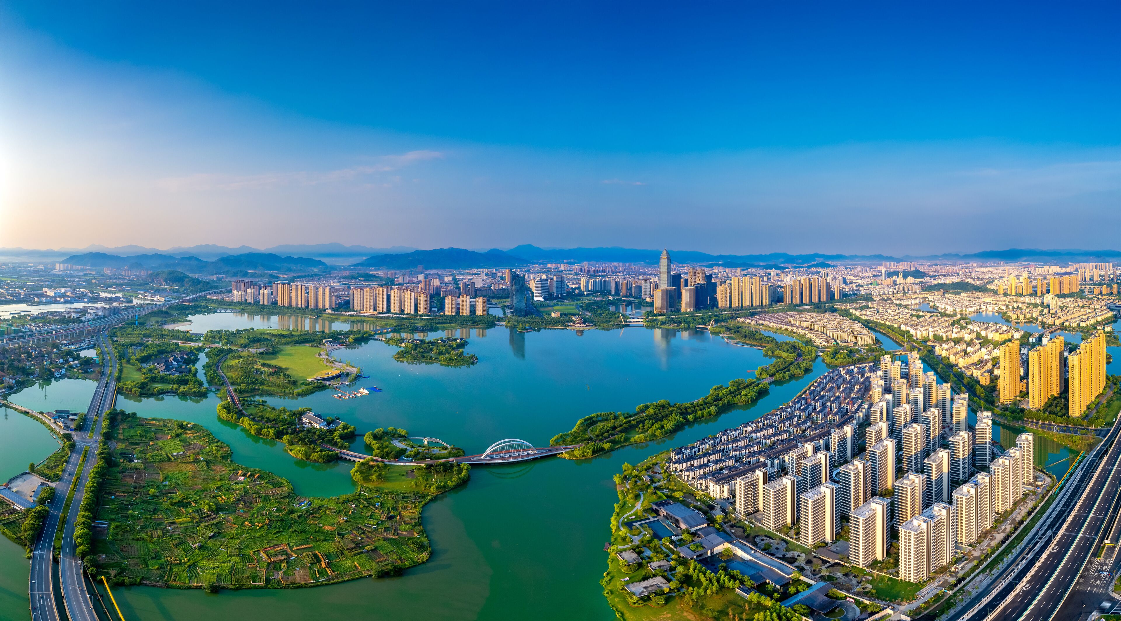 A cityscape with a river, green areas, and high-rise buildings.