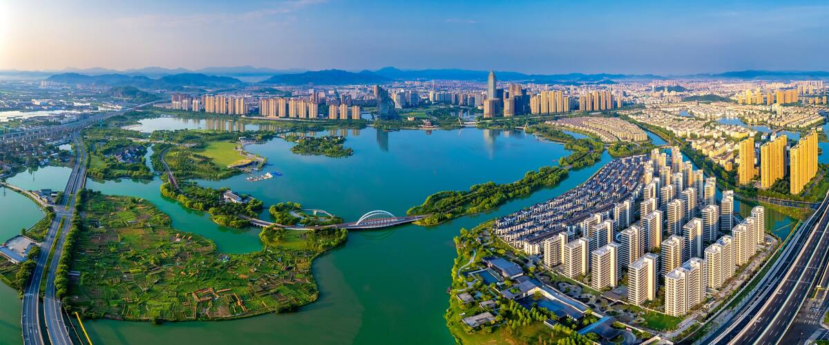 A cityscape with a river, green areas, and high-rise buildings.