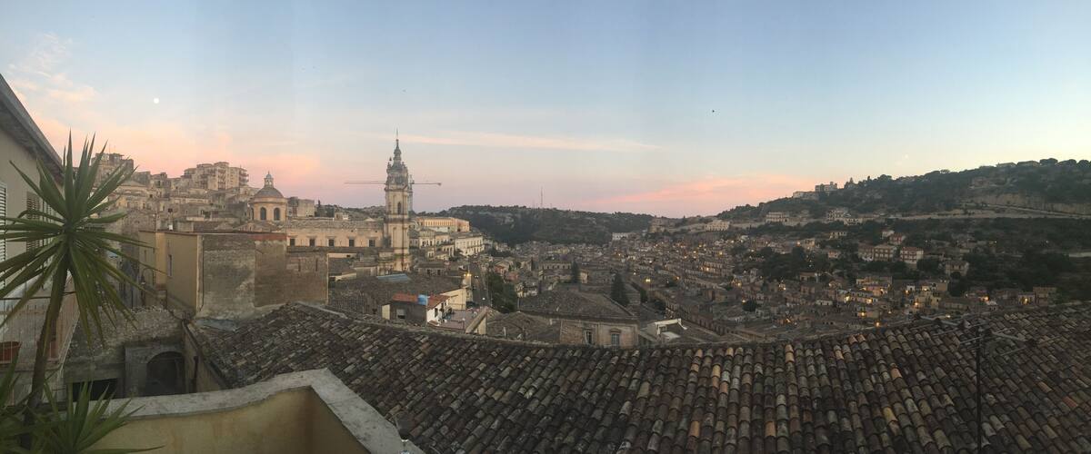 A cityscape with a prominent church, a tower, and terracotta rooftops.