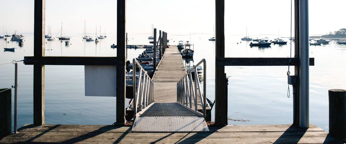 A wooden pier leading to a marina with boats docked.