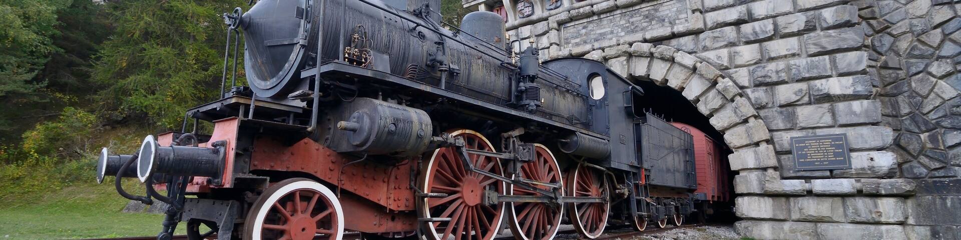 A steam locomotive passing through a stone tunnel.