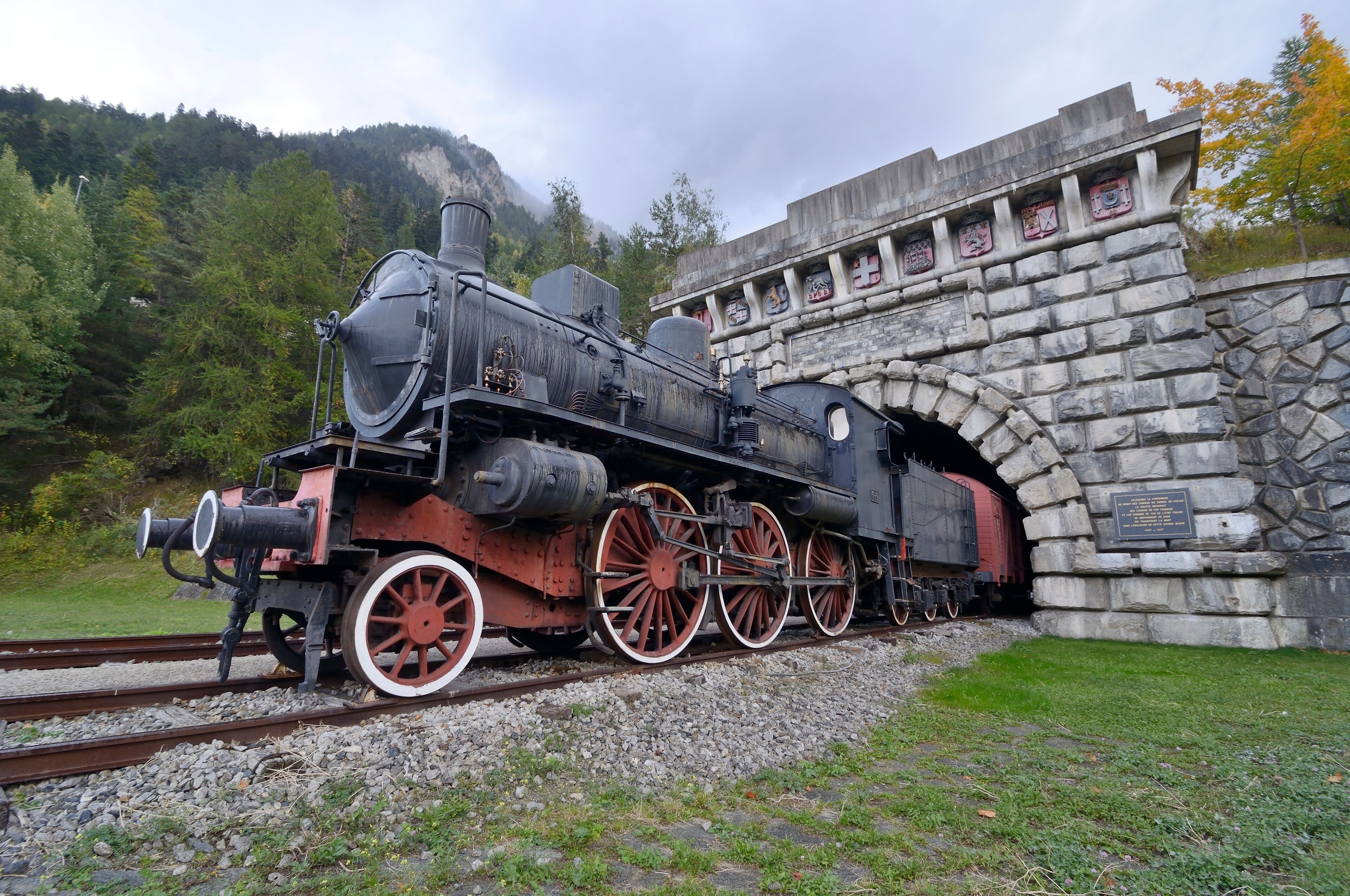 A steam locomotive passing through a stone tunnel.