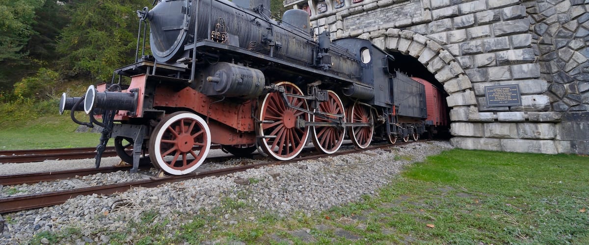 A steam locomotive passing through a stone tunnel.