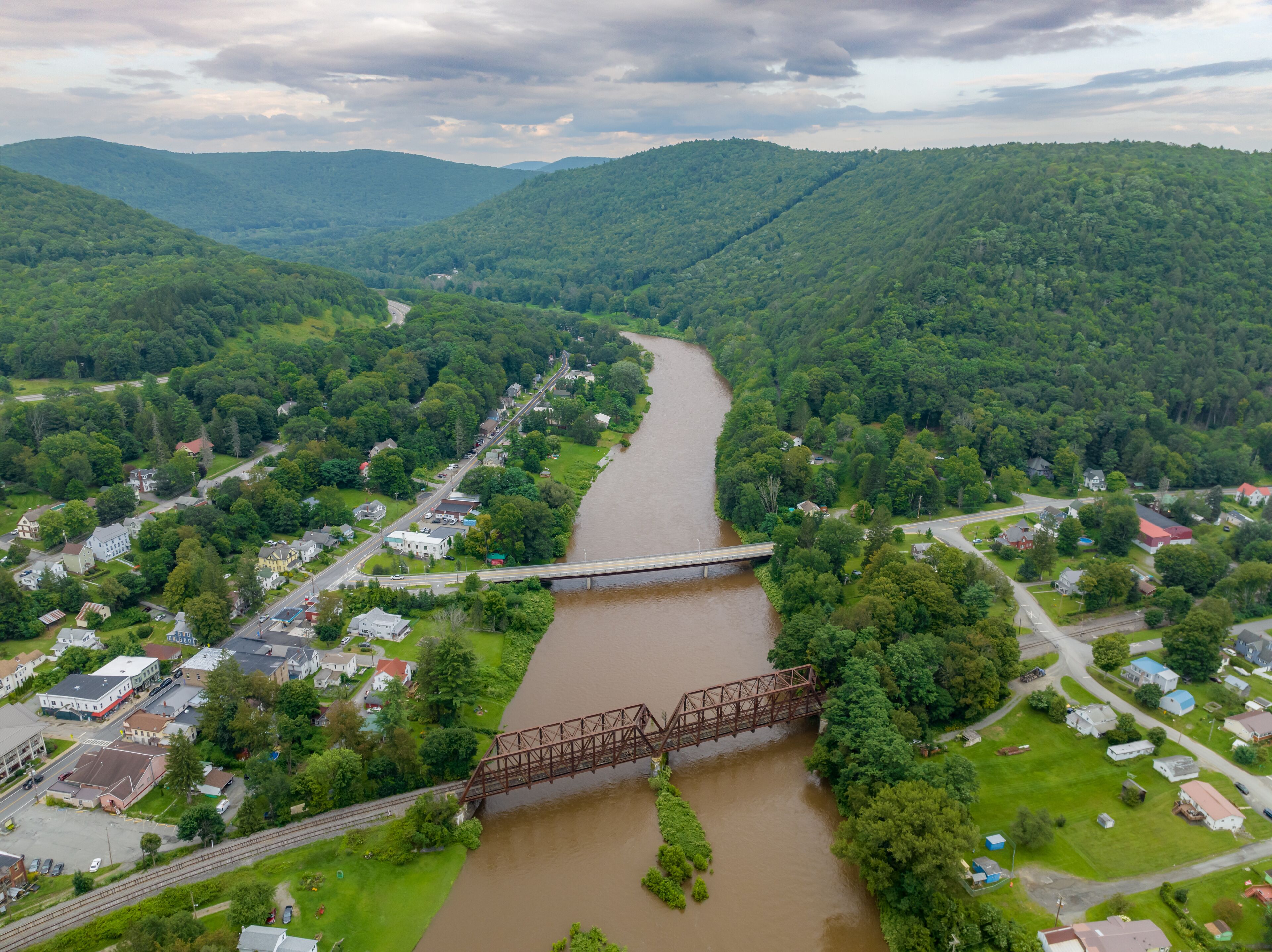 A river flowing through a town surrounded by hills.