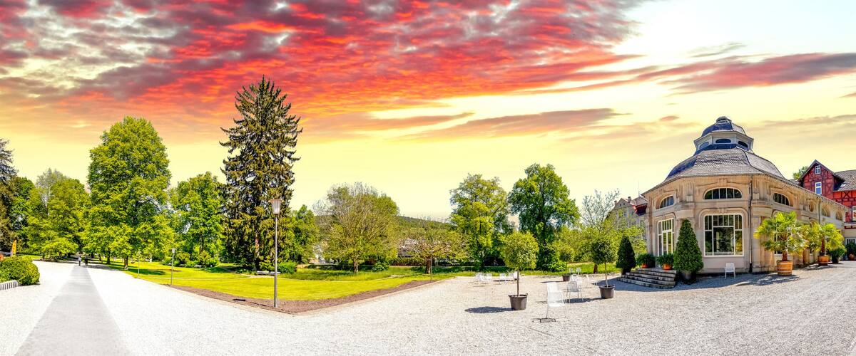A historic building with a dome, surrounded by trees and a gravel path.